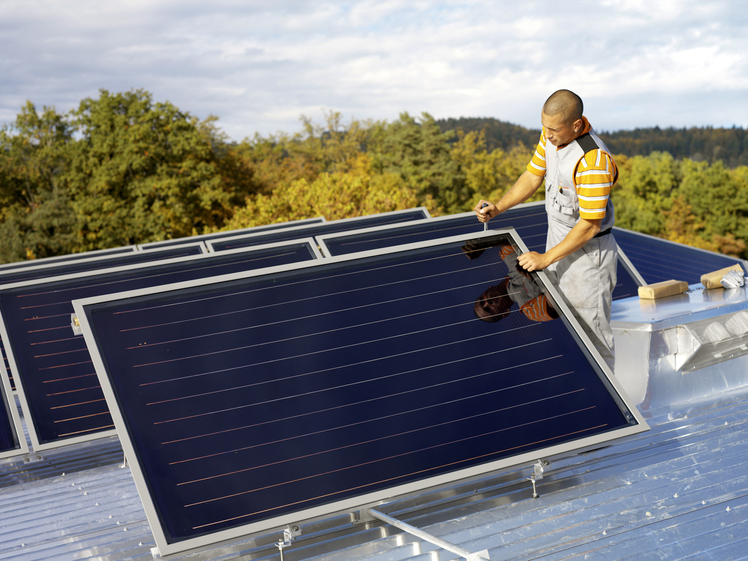 Handwerker montiert Solarkollektor auf Flachdach